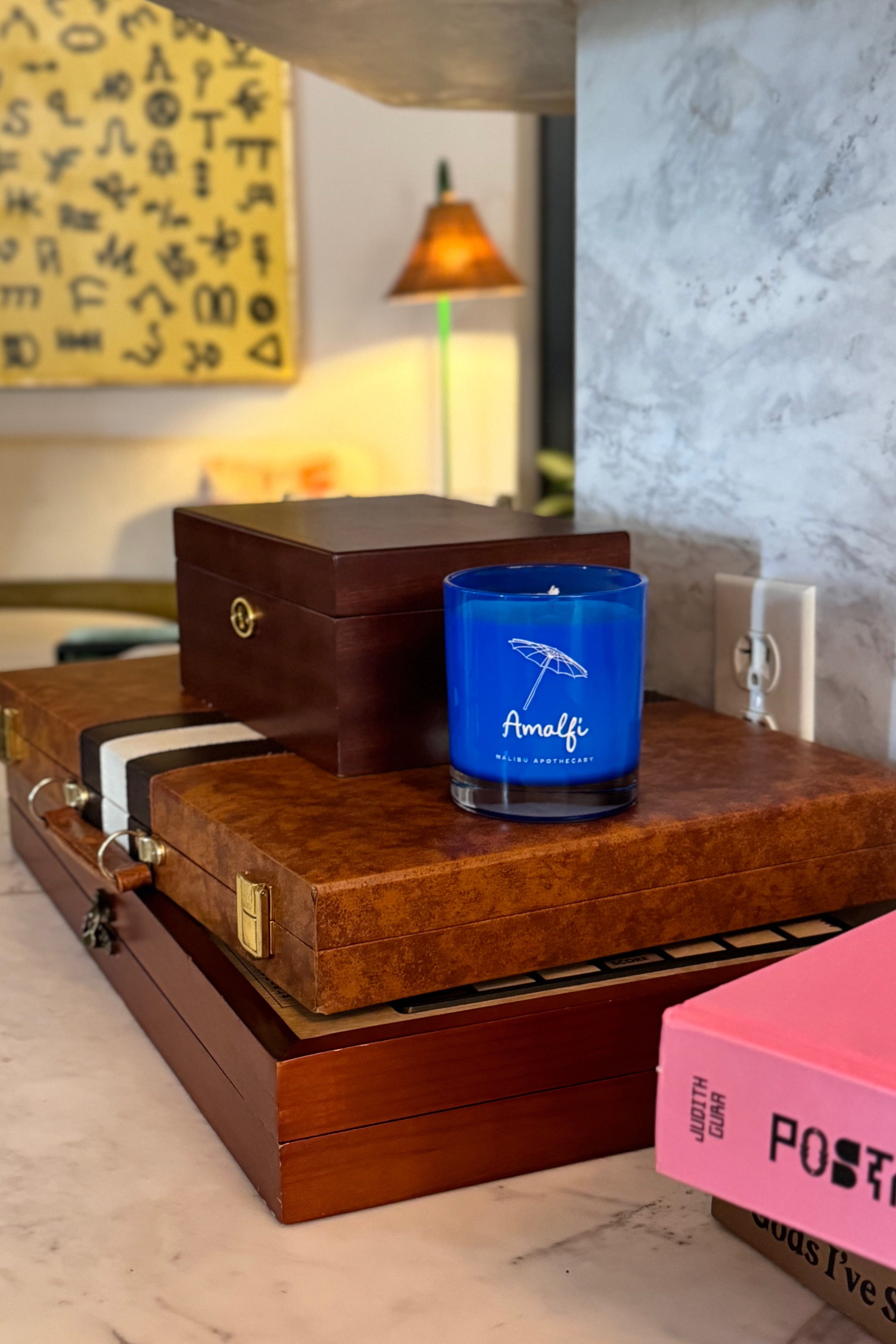 Amalfi blue candle in a bright blue glass jar scented with basil and arugula notes on a mahogany box at hotel in New Orleans