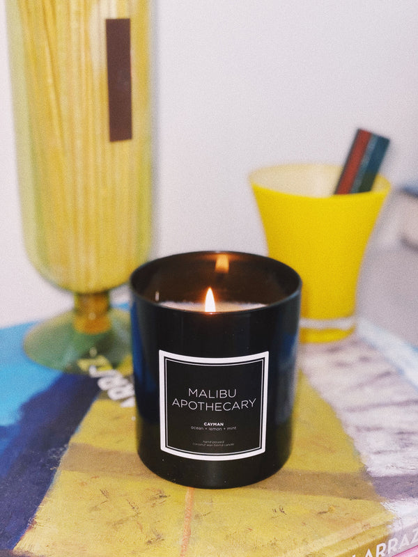 A lit High gloss black candle in hand blown glass next to matches in a living room