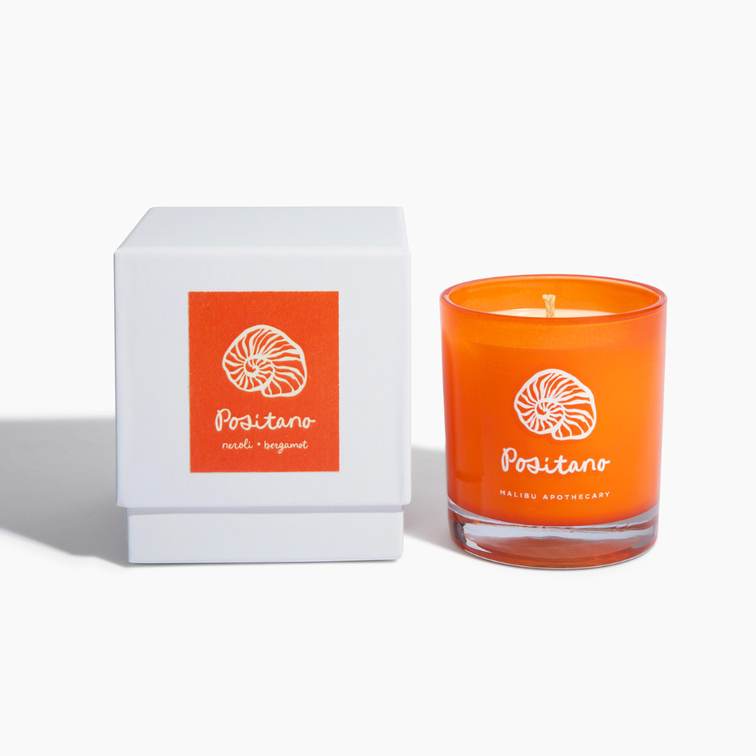 Positano candle with neroli and orange blossom scent in orange glass with shell logo and white box, hand-poured using coconut and soy wax