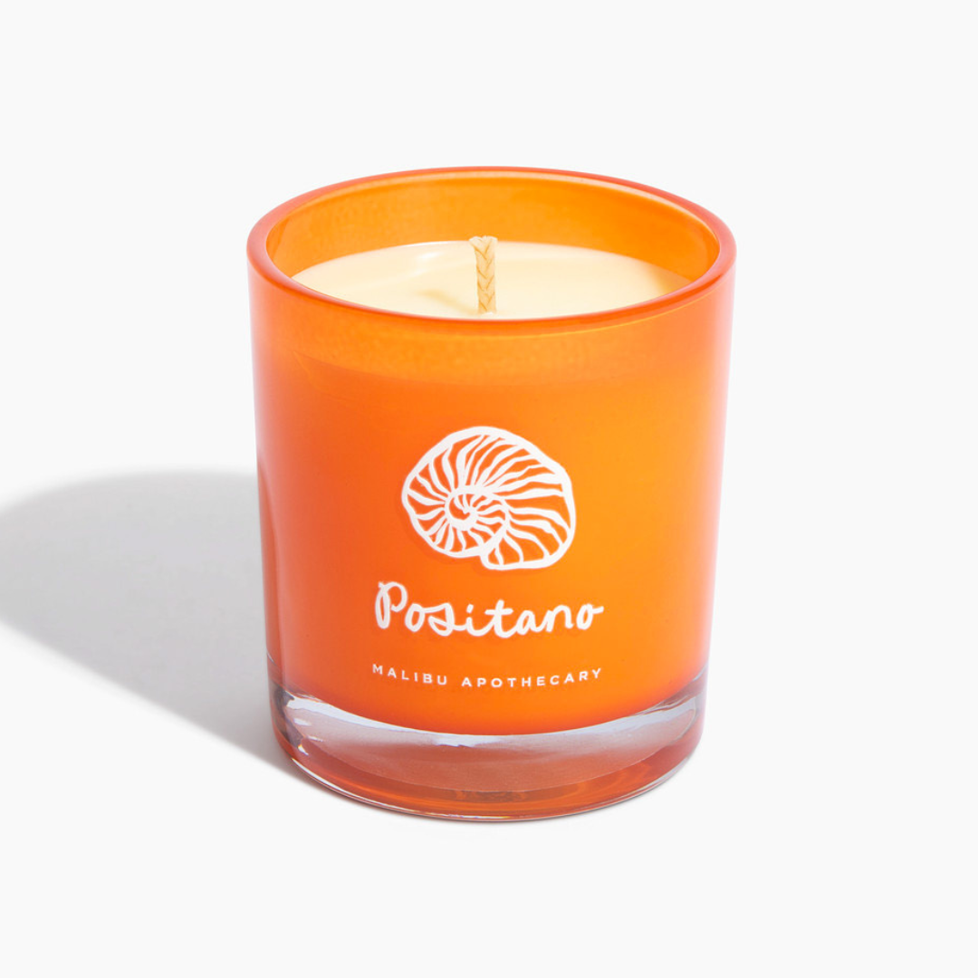 Positano candle in vibrant orange glass jar with shell logo, featuring neroli and orange blossom scent and coconut soy wax