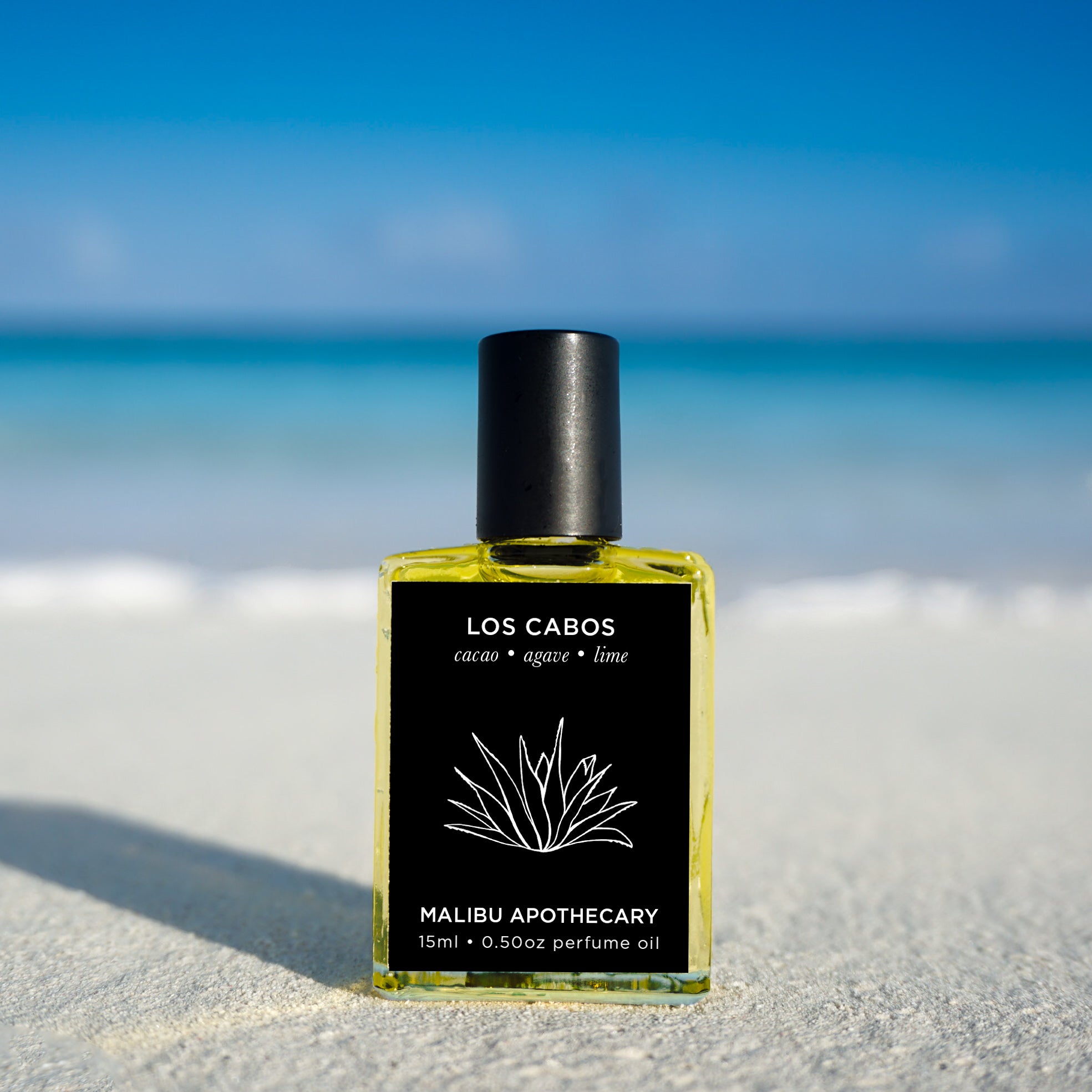 Soleil Roller Perfume sitting on a beach in Turks & Caicos with the ocean in the background