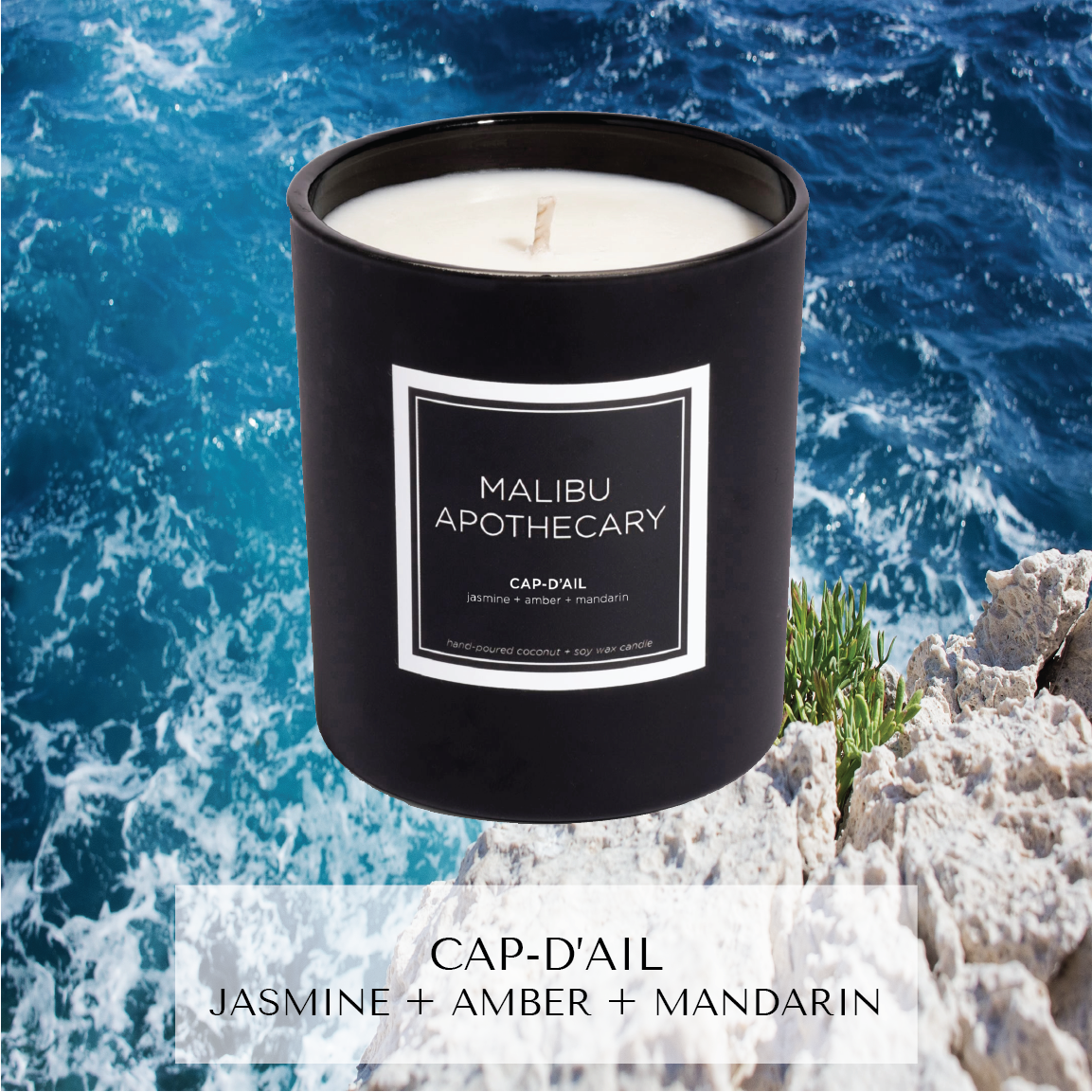 Matte black Malibu Apothecary candle labeled Cap-d'Ail jasmine + amber + mandarin set on a rocky cliff overlooking azure ocean waves, made with all natural coconut and soy wax