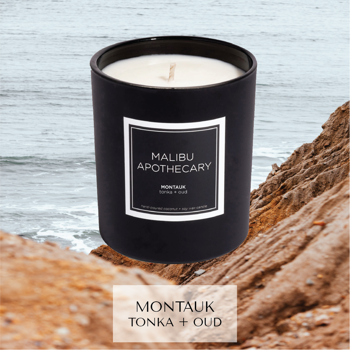 Matte black Malibu Apothecary candle labeled Montauk tonka + oud on a rocky coastline with ocean waves in the background, made with all natural coconut and soy wax