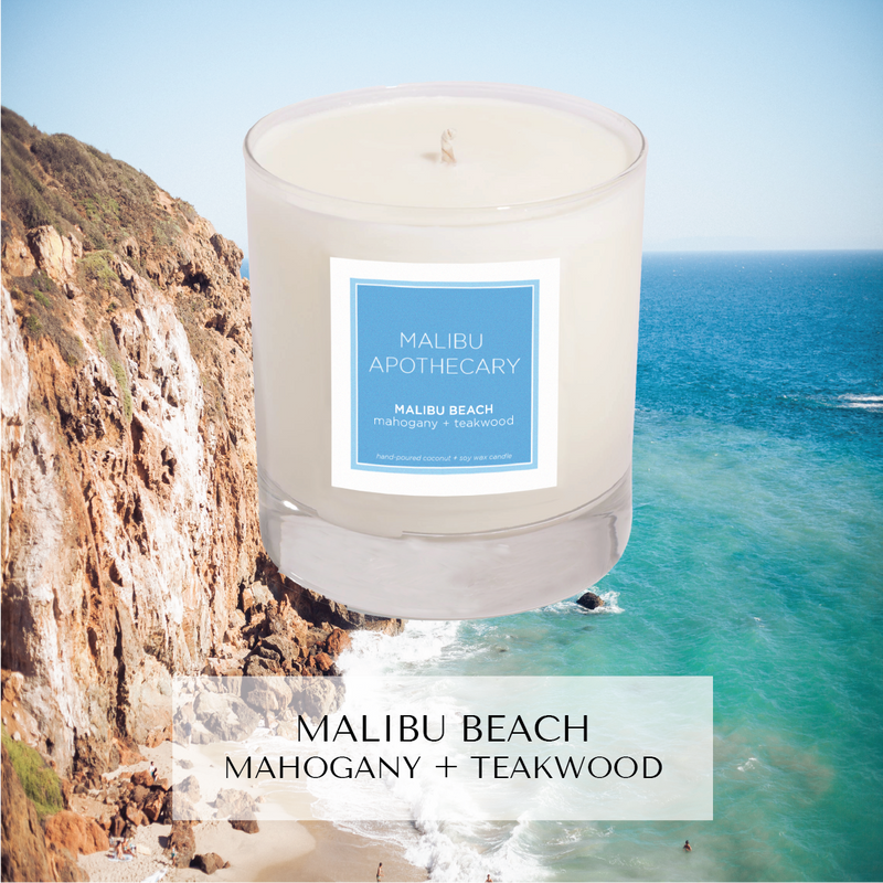 Malibu Beach inspired candle with notes of mahogany and teakwood in Clear gloss x Blue in front of Zuma Beach