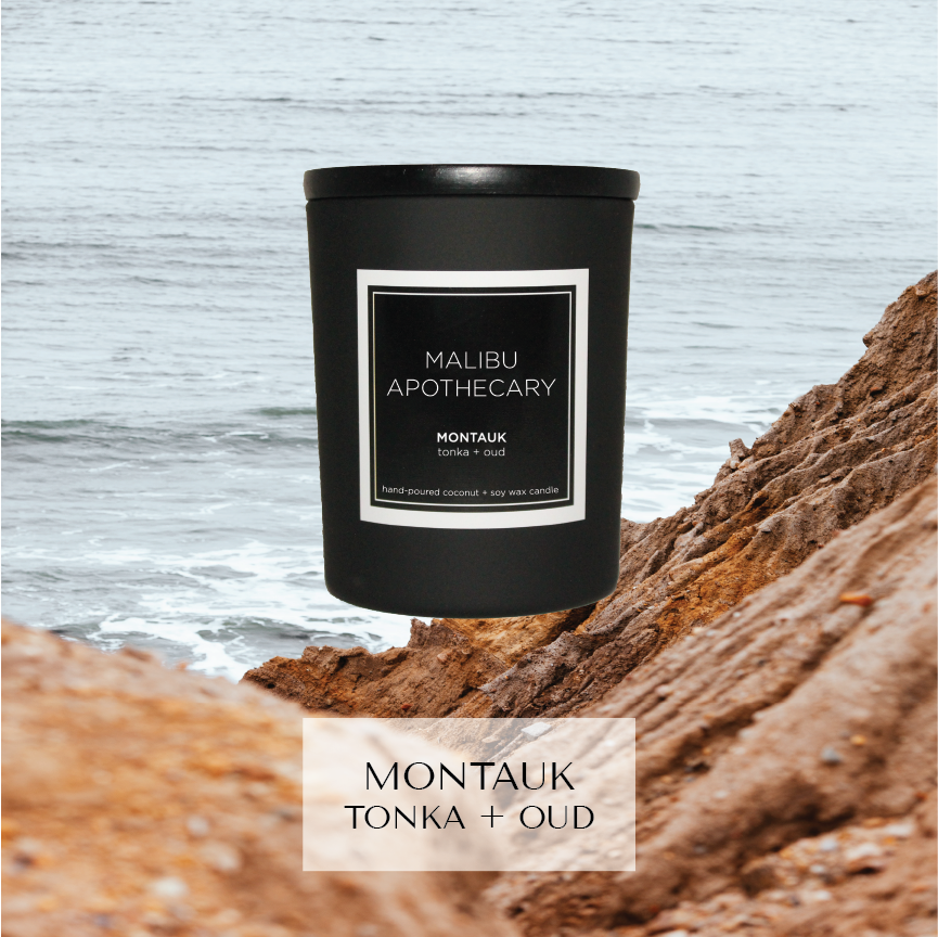 Mini black Malibu Apothecary candle labeled Montauk tonka + oud set on rocky cliff overlooking ocean at Montauk, made with all natural coconut and soy wax