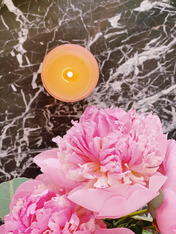 A Pink Scented Candle from Malibu Apothecary next to pink peonies