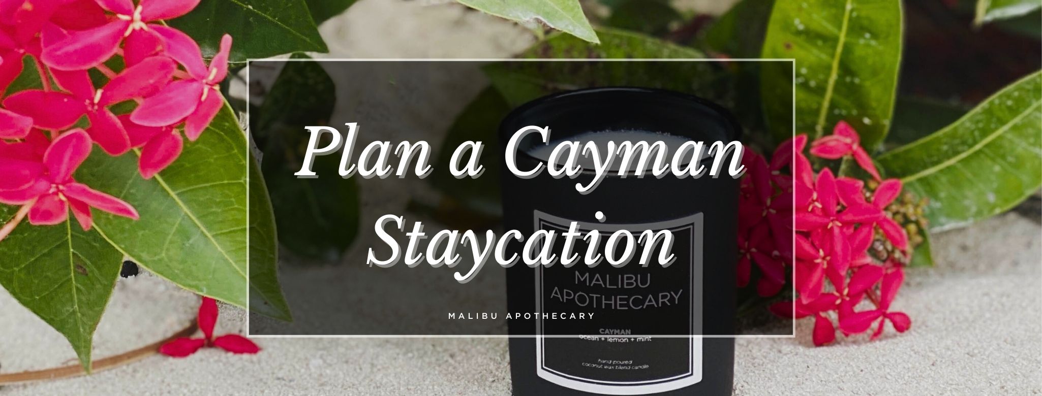 Malibu Apothecary Cayman candle on beach sand surrounded by tropical flowers – blog hero image for how to plan a Cayman Islands-inspired staycation at home using coastal scents, themed drinks, a curated playlist, and luxury candles