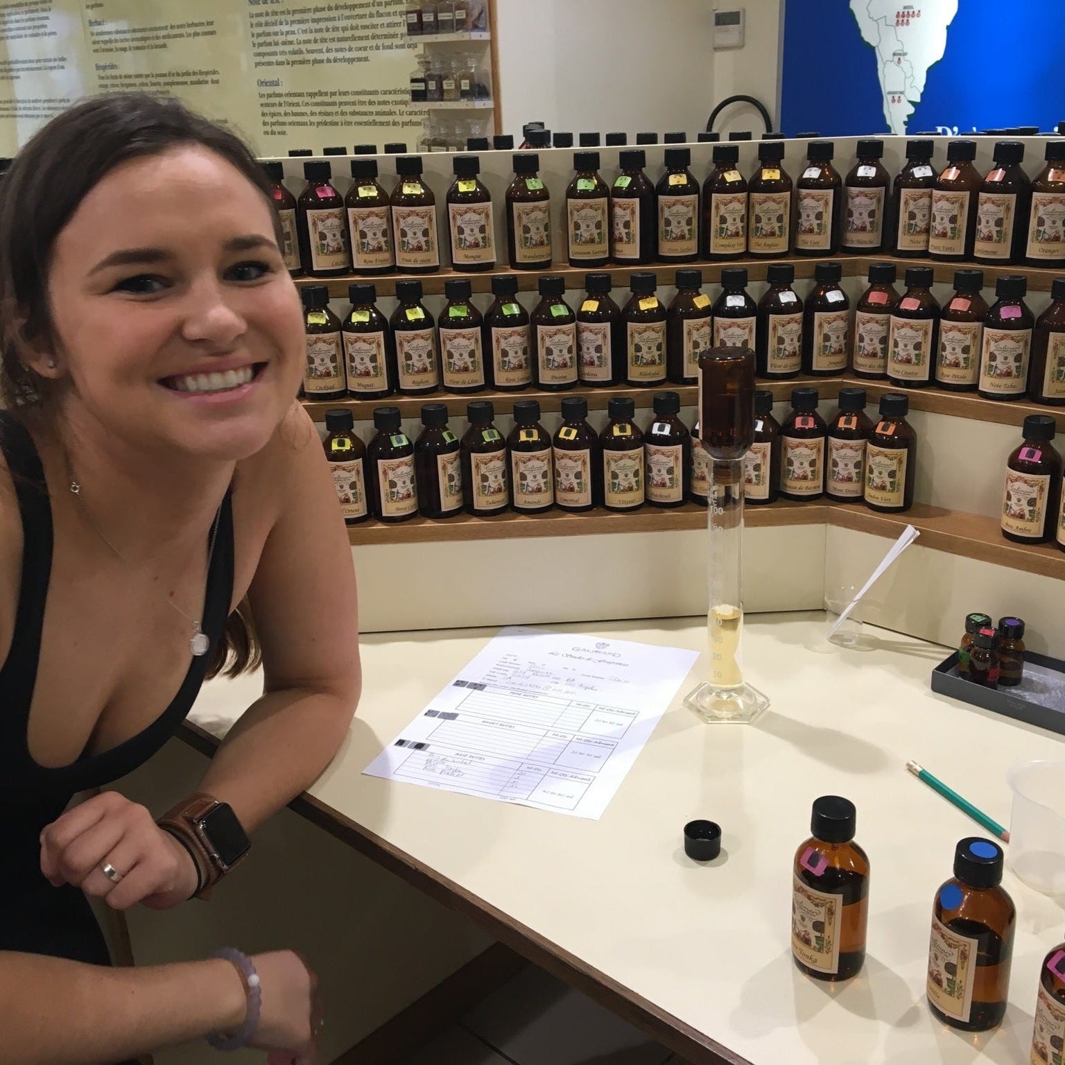 Claire Ellis sitting at a perfumers organ with various bottles of essential oils behind her in a perfumery in Grasse, France
