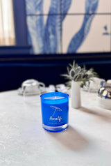 A scented candle with notes of basil and arugula inspired by the Amalfi coast in a bright blue acqua glass jar