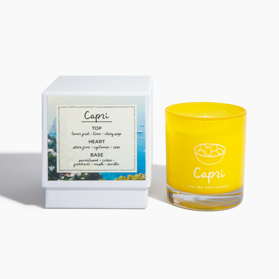 Capri candle in vibrant yellow glass jar with lemon design alongside matching white box featuring Capri fragrance note card; notes of lemon peel, lime, clary sage, cyclamen and rose; candle made with all natural coconut and soy wax