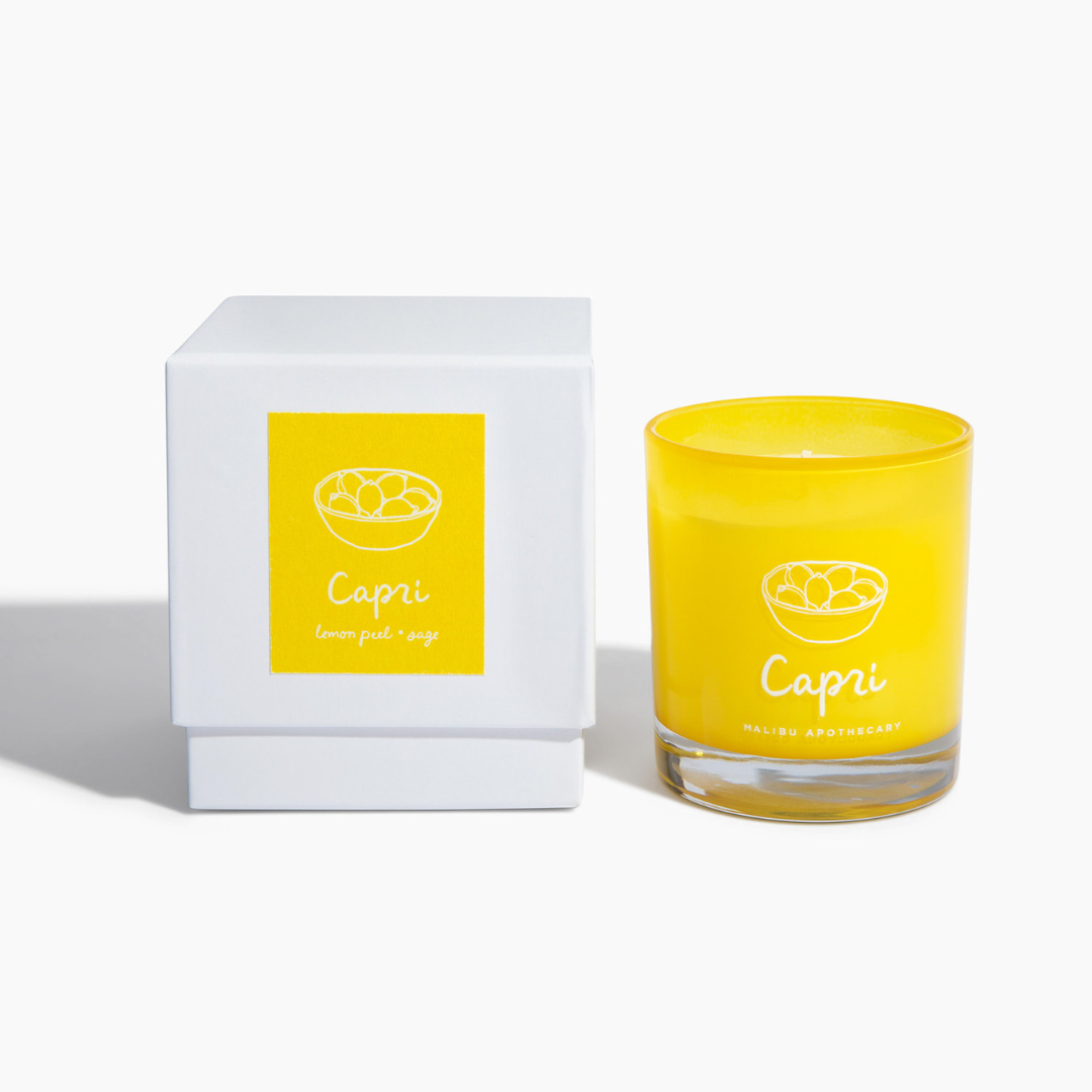 Capri candle in bright yellow glass jar with lemon graphic next to matching white box featuring yellow front label and Capri lemon peel & sage tagline; clean non-toxic candle made with all natural coconut and soy wax