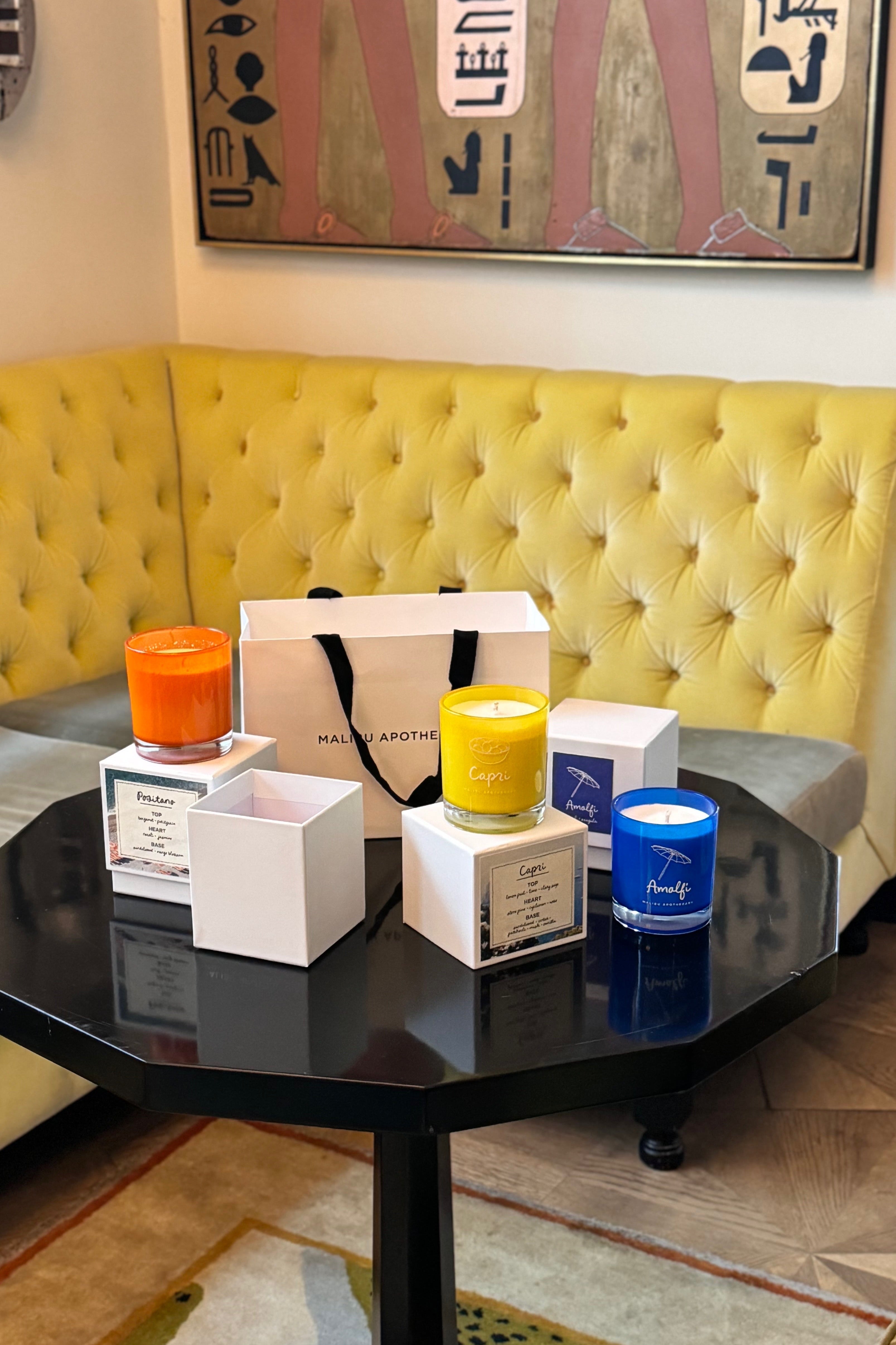 A group of Italian inspired candles sitting on a table. There are 3 scented candles inspired by Amalfi, Positano, and Capri with notes of basil, arugula, lemon peel, orange blossom and neroli. 