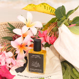 Los Cabos Roller Perfume created by Malibu Apothecary sitting on a gift bag with flowers of background.