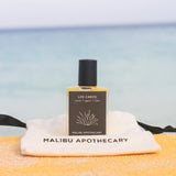 Los Cabos Roller Perfume created by Malibu Apothecary sitting on a gift bag with a sea of background.