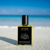 Soleil Roller Perfume sitting on a beach in Turks & Caicos with the ocean in the background