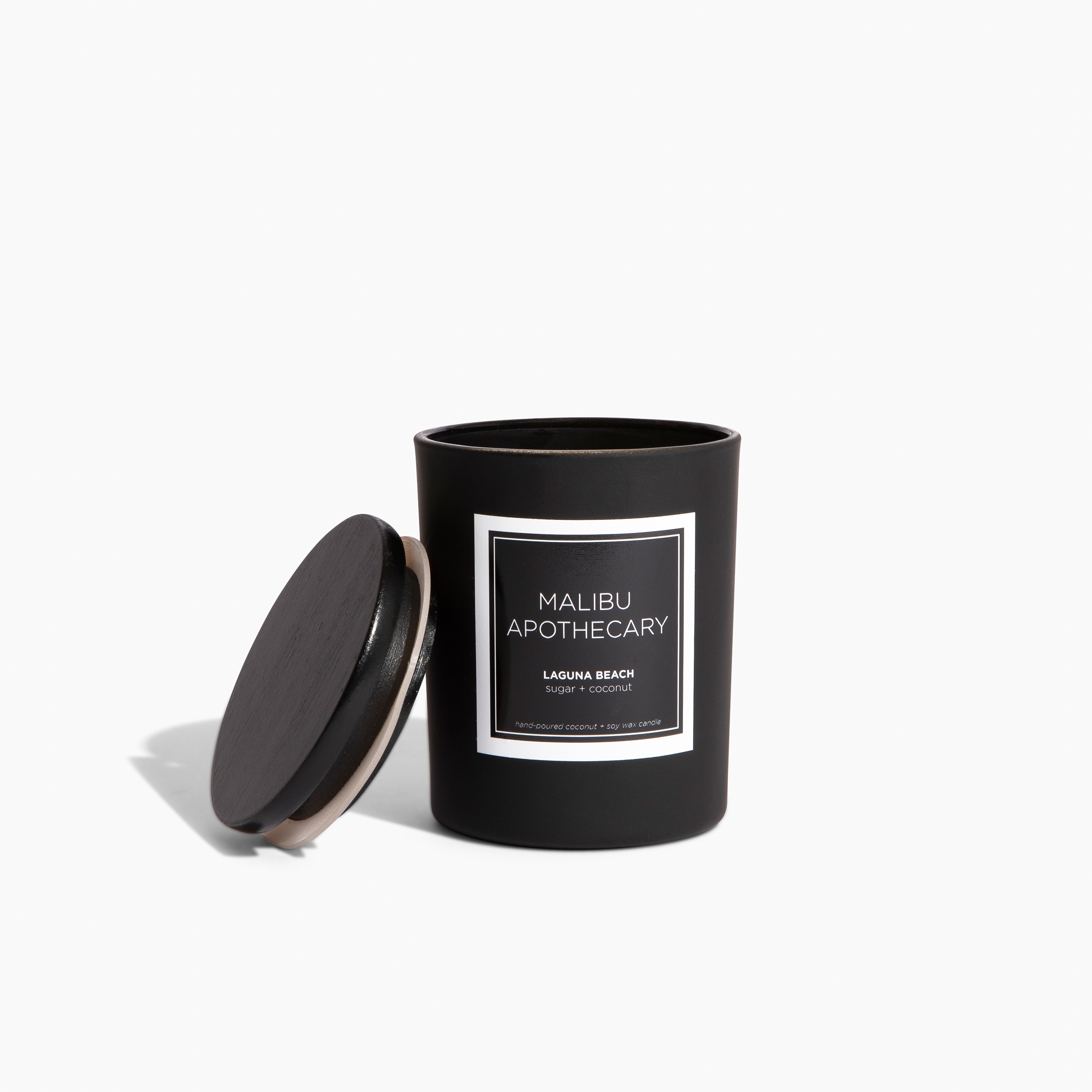 Mini matte black Malibu Apothecary candle in sleek black vessel with coconut and soy wax and matching lid, pictured on a white background with soft shadow, in Laguna Beach scent