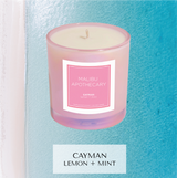 Cayman islands inspired candle with notes of lemon, mint, sea mist, ocean air in iridescent pink in front of ocean pciture