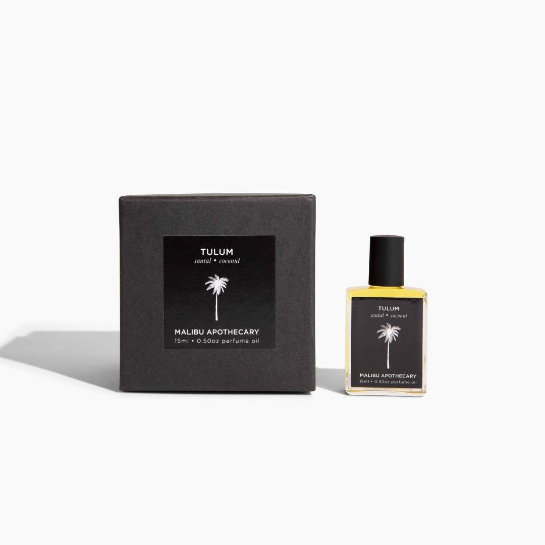 Soleil Roller Perfume in Tulum scent with notes of santal and coconut, presented with a matte black gift box; yellow glass bottle infused with organic golden jojoba oil and natural essential oils